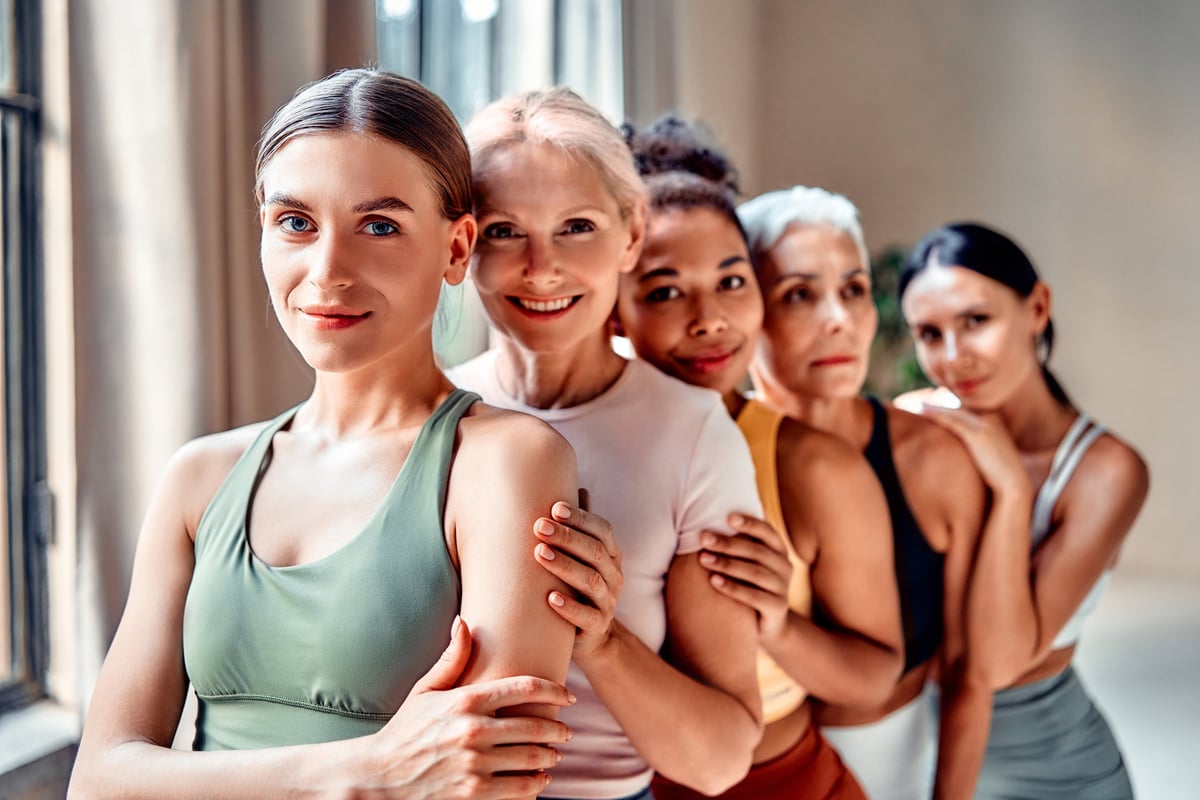 Diverse women of different ages smiling together in activewear, wellness and community concept