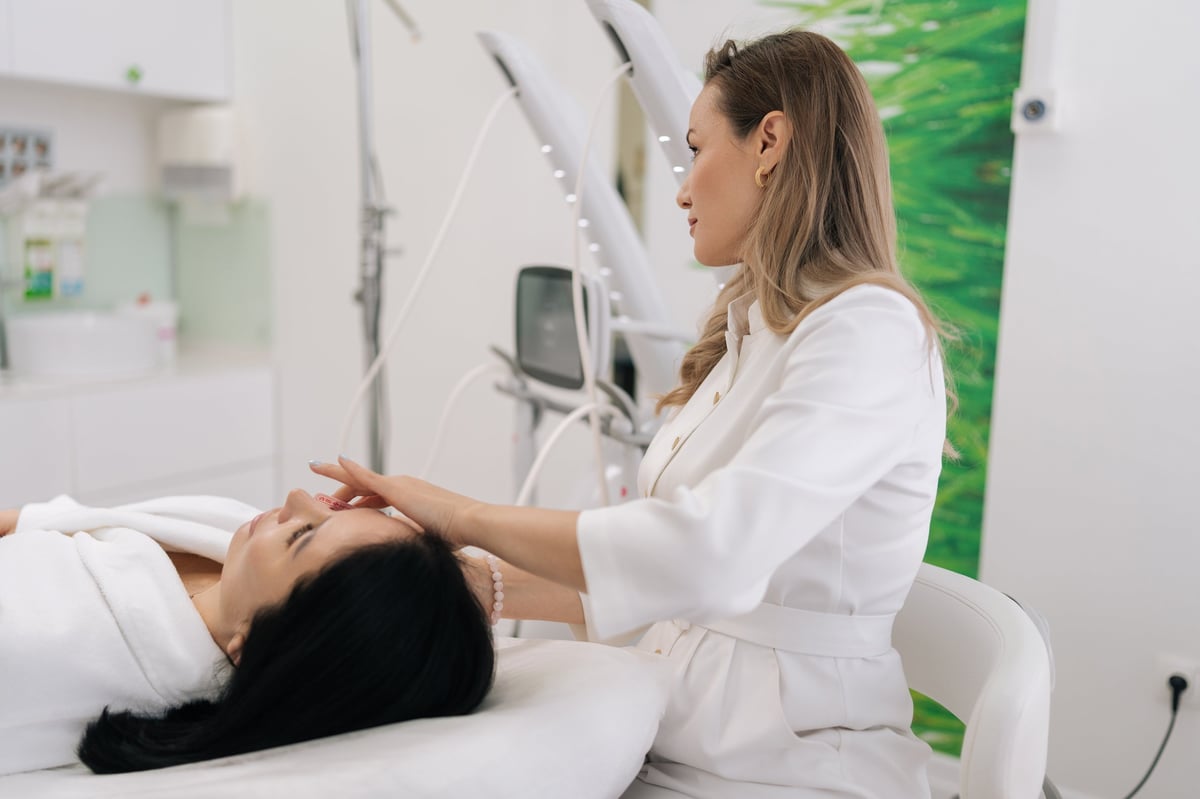 Skilled cosmetologist female performing microneedling with mesotherapy serum on woman face in professional clinic, promoting collagen, skin rejuvenation, lifting and glowing anti-aging results.