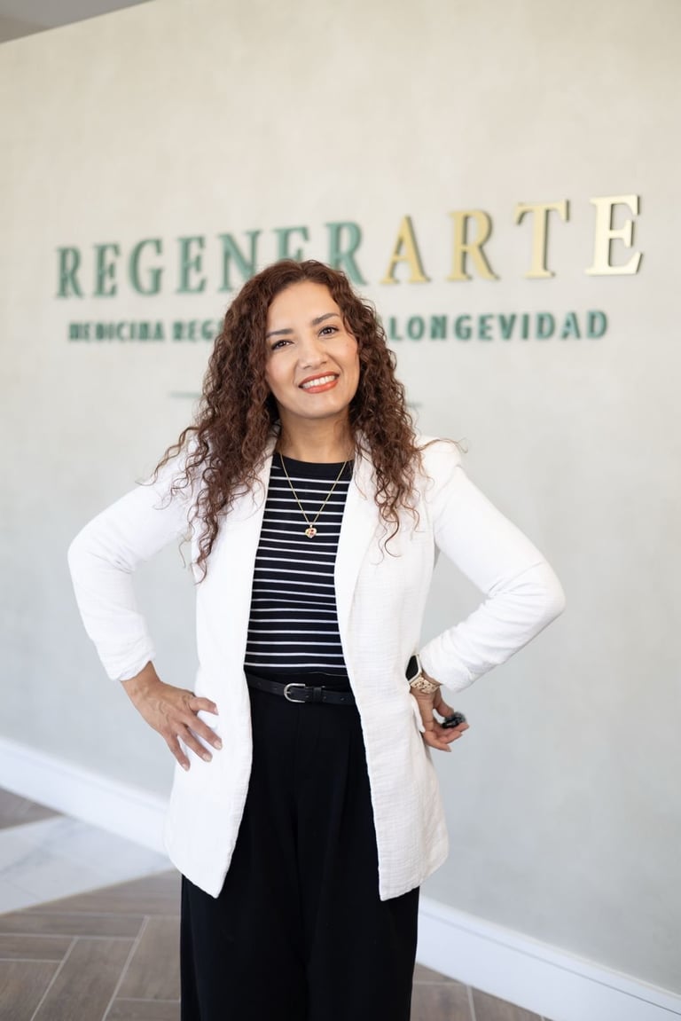 Woman with curly brown hair wearing a white blazer and striped top standing in front of a Regenerarte clinic sign
